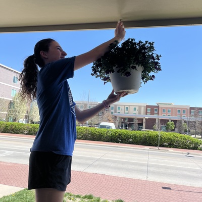 Audrey Cook hanging flower baskets at the Manhattan Emergency Shelter during the 2023 Youth Volunteer Day